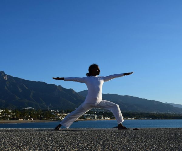A silhouette of a person in a deep stretch yoga pose at sunrise.